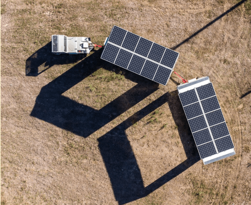Photo aérienne d'un véhicule électrique avec 2 remorques équipées de panneaux solaires